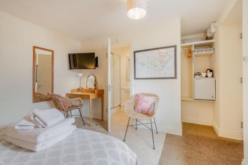1 dormitorio con cama, sillas y escritorio en The Garden Room en Eastbourne