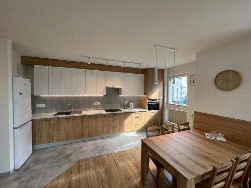 a kitchen with a wooden table and a refrigerator at Apartament U Wujka Żukowo in Żukowo
