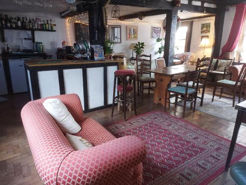 uma sala de estar com um sofá, uma mesa e cadeiras em The Swan Inn em Harwich