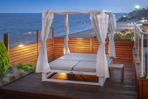 a swinging bed on a deck with the beach at GHT Maritim in Calella