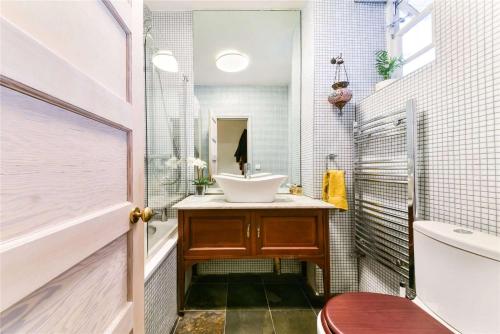 La salle de bains est pourvue d'un lavabo, de toilettes et d'un miroir. dans l'établissement Designer Flat in Bethnal Green, à Londres