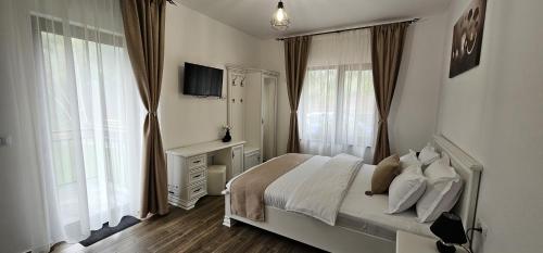 een slaapkamer met een bed met witte lakens en kussens bij Arizona Ranch in Râșca