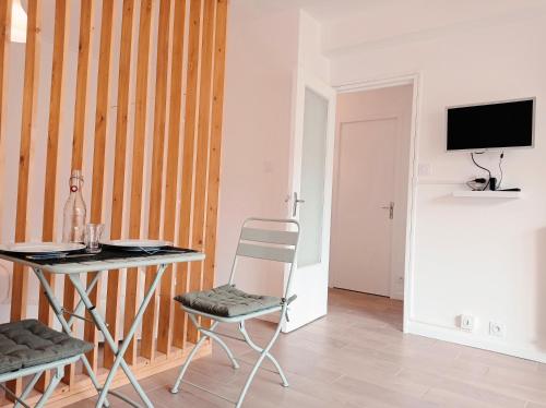 een kamer met een tafel, een stoel en een televisie bij Appartement de charme à Digoin in Digoin