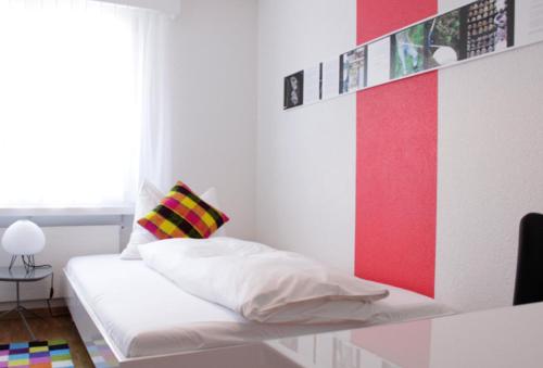 Bett in einem Zimmer mit einer roten und weißen Wand in der Unterkunft Nest - Lauriedstrasse 1 in Zug