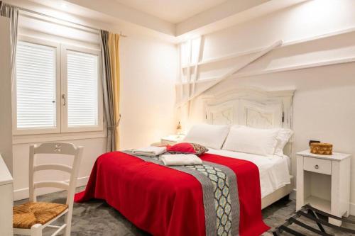 een witte slaapkamer met een rode deken op een bed bij Lughia in Tortolì