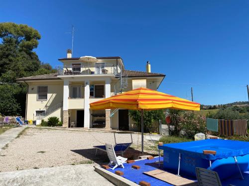dom z parasolem, stołem i krzesłami w obiekcie Casa vacanze Podere Bellavista w mieście Monteprandone
