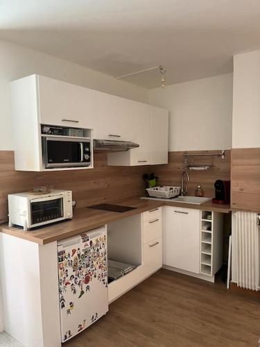 a kitchen with white cabinets and white appliances at Petit deux pièces avec piscine in Vallauris