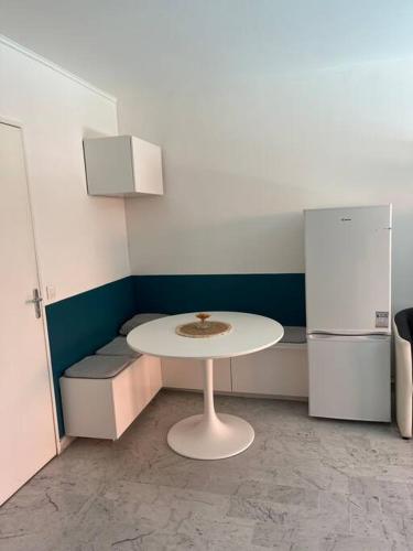 a small kitchen with a white table and a refrigerator at Petit deux pièces avec piscine in Vallauris