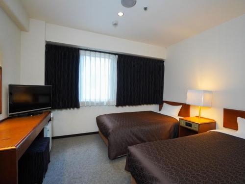 a hotel room with two beds and a flat screen tv at Plaza Hotel Tenjin in Fukuoka