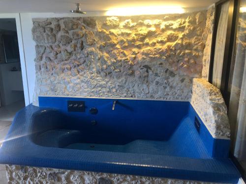- une baignoire bleue dans une chambre dotée d'un mur en pierre dans l'établissement Isola Bella view, à Tropea