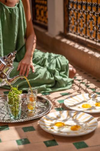 uma mulher sentada numa mesa com pratos de comida em Riad Le Petit Bacha em Marraquexe