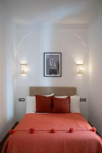 a bedroom with a bed with red sheets and two lights at Riad Le Petit Bacha in Marrakesh