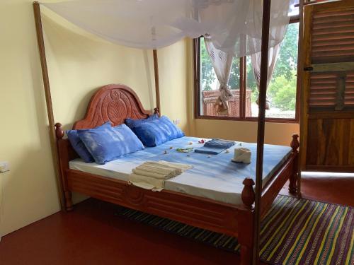 a bedroom with a canopy bed with blue pillows at Mafia Beach Bungalows sea view in Utende