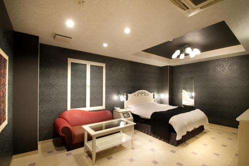 a bedroom with a bed and a red chair at Hotel M in Oyodo