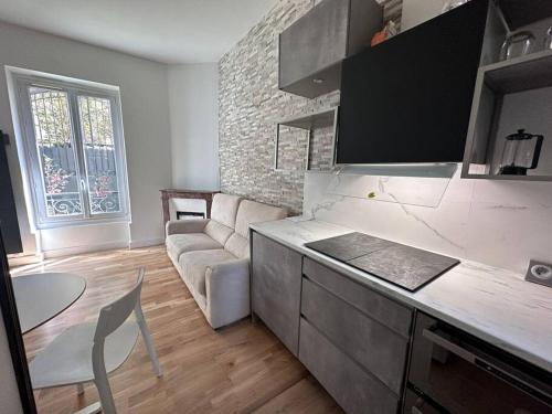 uma cozinha com um sofá e uma mesa num quarto em appartement moderne quai de seine em Neuilly-sur-Seine