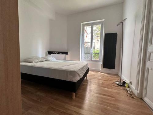 um quarto com uma cama e uma grande janela em appartement moderne quai de seine em Neuilly-sur-Seine