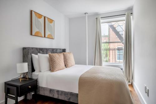 a white bedroom with a bed and a window at East Village 3br w elevator wd nr parks NYC-1209 in New York