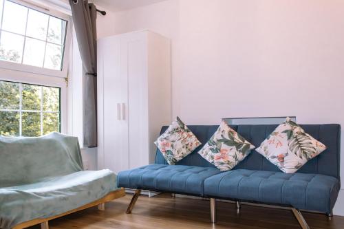 eine blaue Couch in einem Wohnzimmer mit Kissen darauf in der Unterkunft Nice 4 Bedroom Apartment near City Centre 2-min Walk to Metro !! Business & Family Friendly!! in London