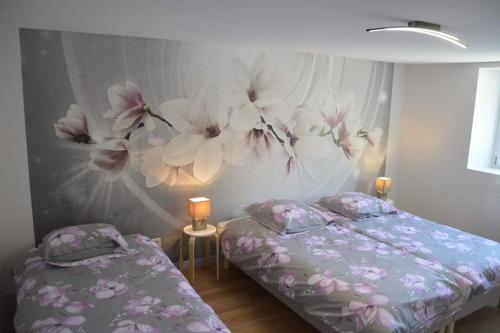 - une chambre avec 2 lits et un mur orné de fleurs dans l'établissement Gîte du Champ De La Pierre, à Faymont