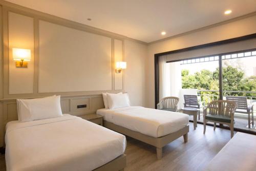 Pinnacle Grand Jomtien Resort and Beach Club - SHA Extra Plus في نا جومتين: غرفة فندقية بسريرين وبلكونة