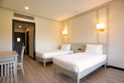 a room with two beds and a table and a desk at Pinnacle Grand Jomtien Resort and Beach Club - SHA Extra Plus in Na Jomtien