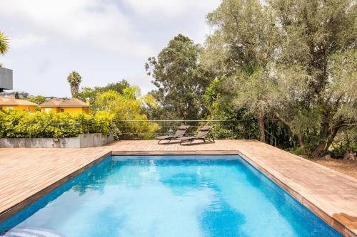 einen Pool mit 2 Stühlen und eine Holzterrasse in der Unterkunft Casa de lujo junto al Club Golf in Tacoronte