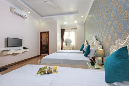 a hotel room with two beds and a tv at Phoenix Hotel Ha Long in Ha Long