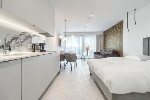 une chambre blanche avec un lit et une cuisine dans l'établissement Sea & Lake - City Apartments, à Mielno