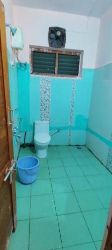 a blue bathroom with a toilet and a window at Feel Lyk Home in Visakhapatnam