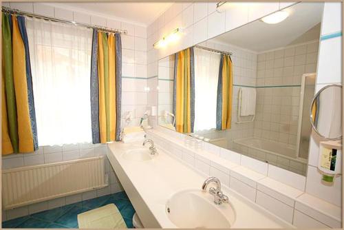 a bathroom with a sink and a mirror and a tub at Relax- & Wanderhotel Poppengut in Hinterstoder