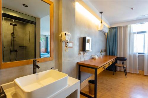 ein Bad mit einem Waschbecken und einem Spiegel in der Unterkunft Gongxili - Chujian Hotel in Kunming