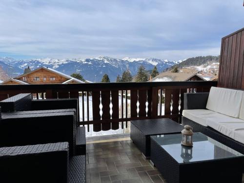 a balcony with a couch and a table and mountains at Appartement - Villars Sur Ollon in Villars-sur-Ollon
