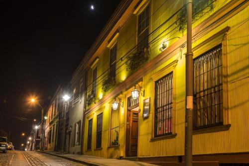 a yellow building with windows on a street at night at Hotel Boutique Acontraluz in Valparaíso