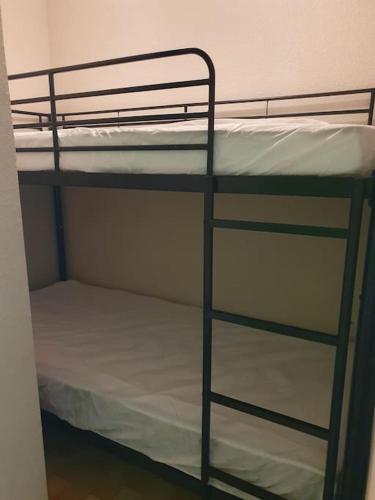 - un lit superposé avec des draps blancs au-dessus dans l'établissement Studio cabine La Lagune Côté Espiguette, au Grau-du-Roi