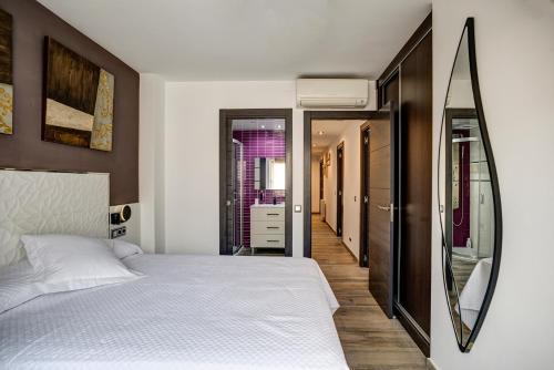1 dormitorio con cama blanca y espejo en Dreams Port Cambrils Apartment en Cambrils