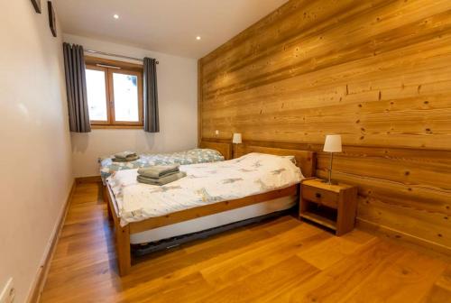 une chambre avec un lit et un mur en bois dans l'établissement Grand Paradis B01 - Modern with great location, à Chamonix-Mont-Blanc