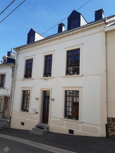 a white building with black windows on a street at Gîte L'Hôte-Antique in Bouillon