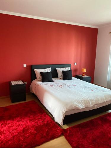 a bedroom with a large bed with a red wall at Maison proche de la mer in Murtosa