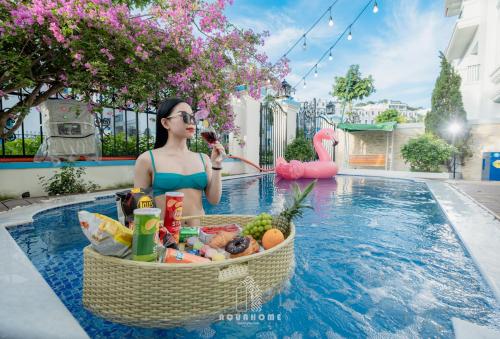 una donna seduta in piscina con un cesto di cibo di The An Nam Villa HaLong a Ha Long