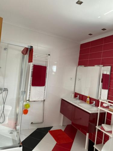 a red and white bathroom with a shower and sink at Maison proche de la mer in Murtosa