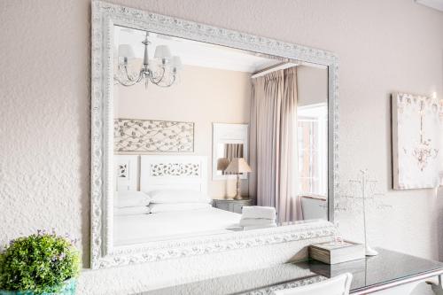 a large mirror in a white room with a bed at Avemore Vredehof No 2 - with Backup Power in Stellenbosch