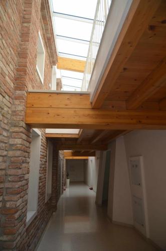 a long hallway with wooden ceilings and a brick wall at Palazzo Maggiore Suite A in Noale