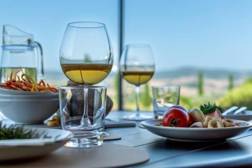 a table with two glasses of wine and a plate of food at AffittiBreviSiena - Palazzo Monaci Appartamento con piscina nelle crete Senesi in Asciano