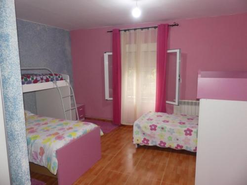1 Schlafzimmer mit 2 Betten und rosa Wänden in der Unterkunft VILLA LOS MOLINOS in Candeleda