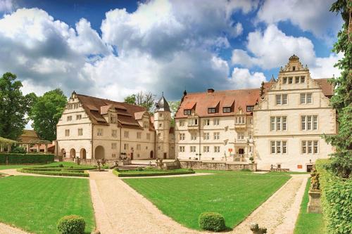 un grand château avec une pelouse verdoyante devant lui dans l'établissement Schlosshotel Münchhausen, à Aerzen