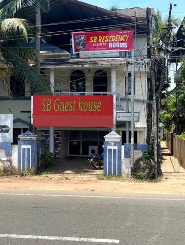 a guest house with a red sign in front of a street at SPOT ON SB Guest House in Alleppey