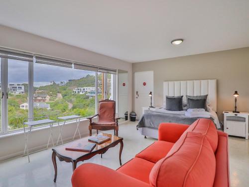 a living room with a bed and a red couch at Glenview Heads Apartments in Knysna