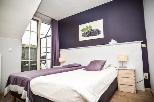 1 dormitorio con 1 cama grande y paredes moradas en B&B Fruithof Tack, en Sint-Gillis-Waas
