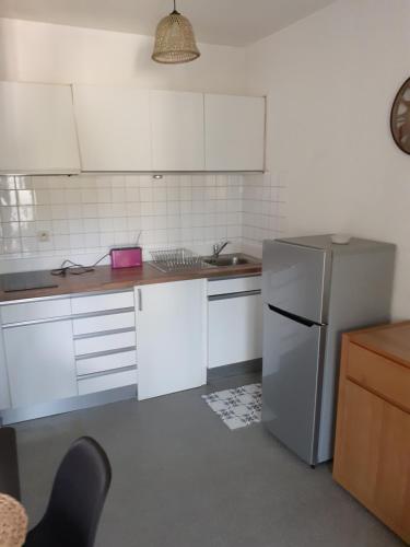 une cuisine avec des armoires blanches et un réfrigérateur en acier inoxydable dans l'établissement Entre terre et mer, à Oloron-Sainte-Marie