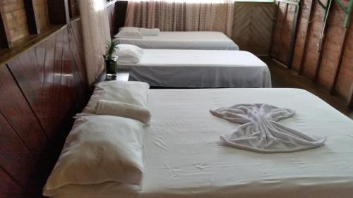 three beds in a room with white sheets and towels at Posada Ecoturística El Valle in El Valle